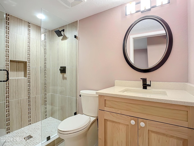 bathroom with a shower with door, vanity, and toilet