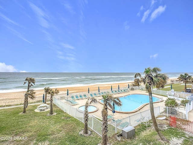 exterior space with cooling unit, a water view, a patio area, a beach view, and a lawn