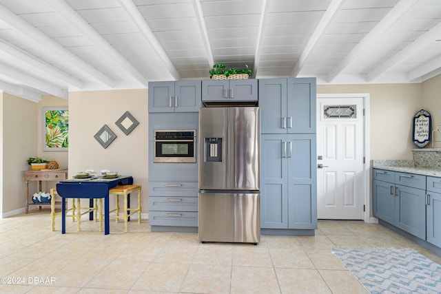 kitchen with beamed ceiling, light tile patterned floors, stainless steel appliances, and light stone counters