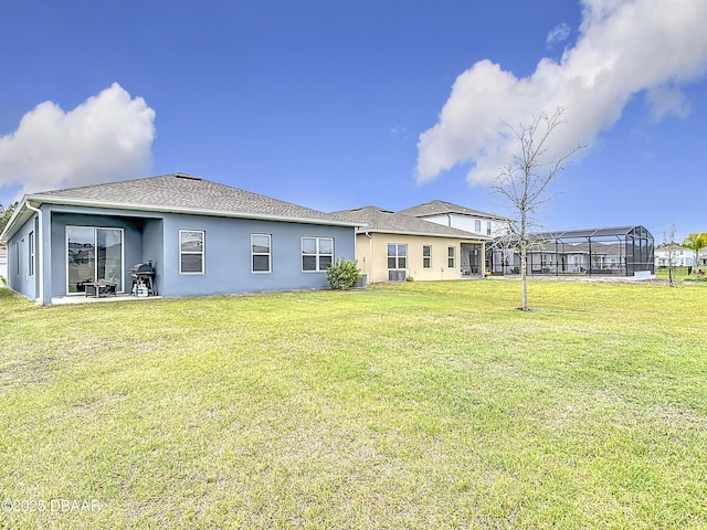 rear view of property featuring a yard, roof with shingles, and stucco siding