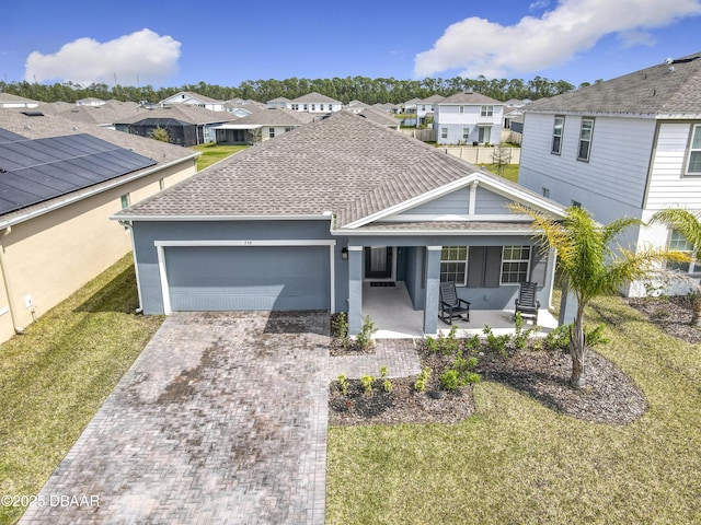 ranch-style home featuring decorative driveway, a residential view, a front yard, a shingled roof, and a garage