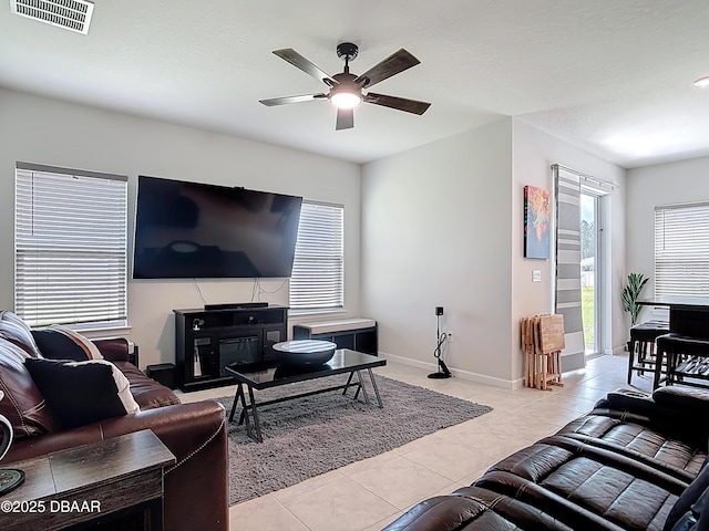 living room featuring light tile patterned floors, a ceiling fan, visible vents, and baseboards