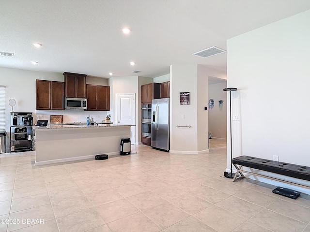 kitchen featuring a center island with sink, dark brown cabinets, visible vents, and stainless steel appliances