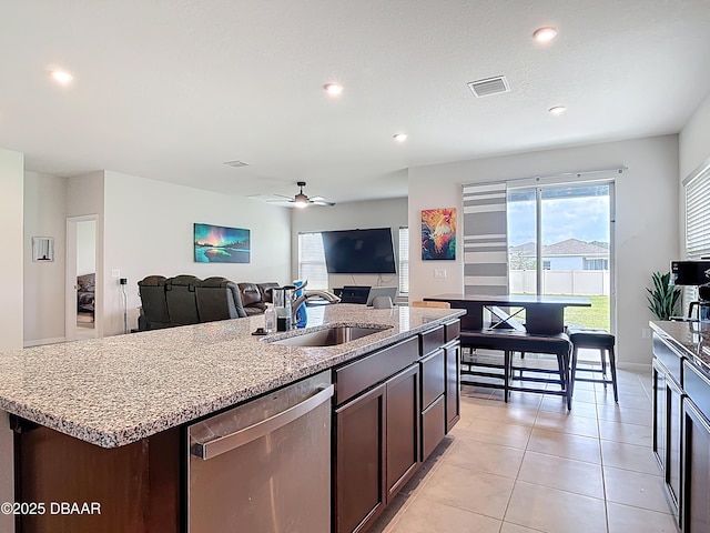 kitchen featuring visible vents, dishwasher, an island with sink, light tile patterned floors, and a sink