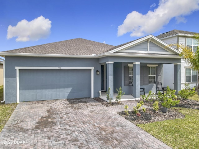 view of front of property with a porch, decorative driveway, an attached garage, and stucco siding