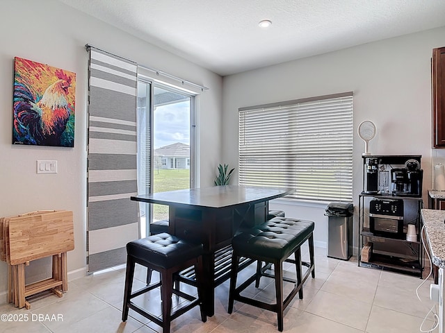 dining area featuring light tile patterned floors, baseboards, and a textured ceiling