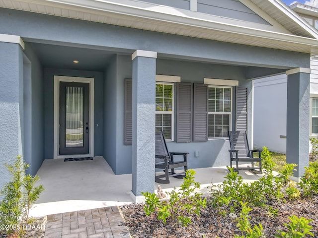 view of exterior entry featuring stucco siding and a porch