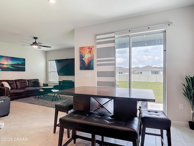 dining space with light tile patterned floors, baseboards, and ceiling fan