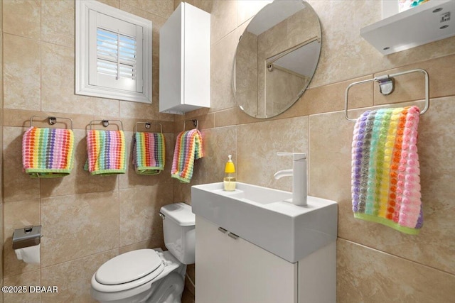 bathroom with toilet, tile walls, and vanity