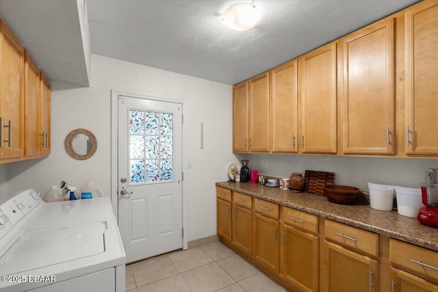 washroom with light tile patterned floors, cabinets, and washer and dryer