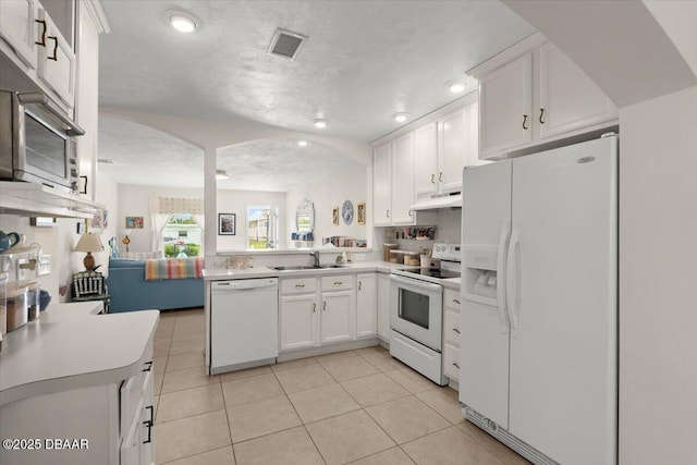 kitchen with sink, white appliances, white cabinets, and kitchen peninsula