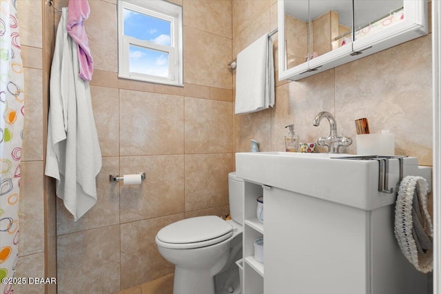 bathroom featuring toilet, vanity, and tile walls