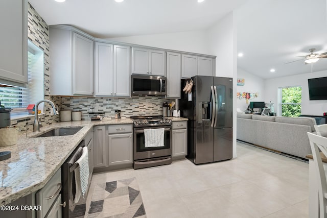 kitchen with vaulted ceiling, sink, tasteful backsplash, gray cabinets, and appliances with stainless steel finishes