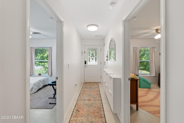 entryway with ceiling fan, plenty of natural light, light tile patterned floors, and a textured ceiling