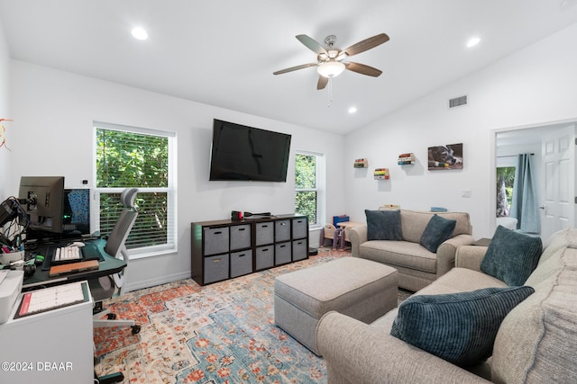 living room with a wealth of natural light, ceiling fan, and vaulted ceiling