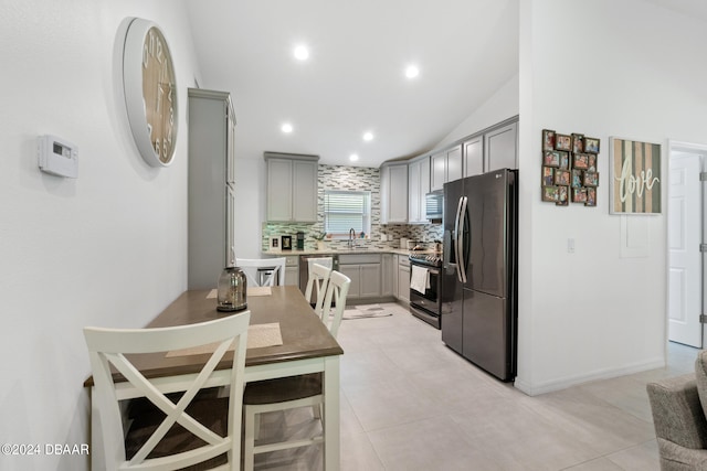 kitchen featuring appliances with stainless steel finishes, tasteful backsplash, light tile patterned floors, lofted ceiling, and gray cabinetry