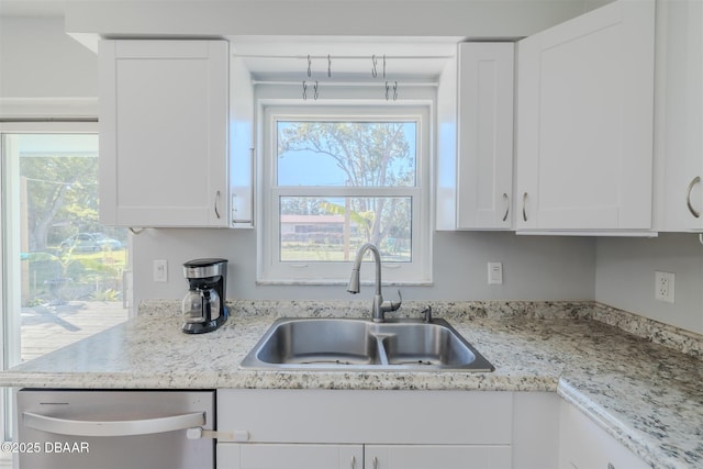 kitchen featuring dishwasher, light stone counters, white cabinets, and a sink