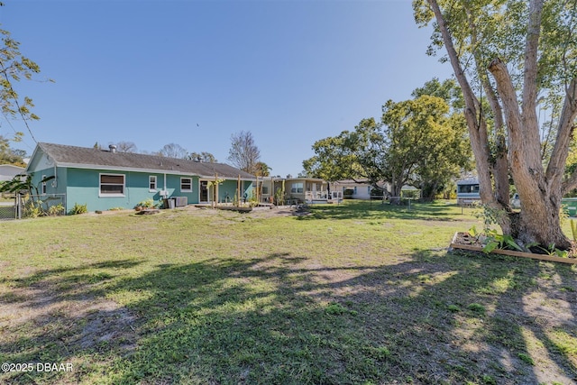 rear view of property featuring a lawn, fence, and stucco siding