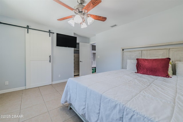 bedroom featuring light tile patterned floors, visible vents, a barn door, ceiling fan, and baseboards