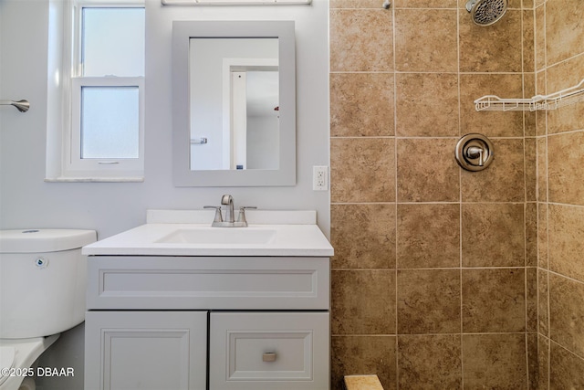 full bathroom with a tile shower, vanity, and toilet