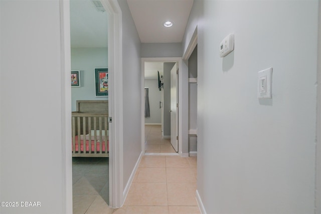 hallway featuring light tile patterned floors, baseboards, visible vents, and recessed lighting