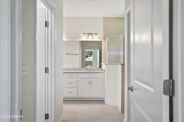 bathroom with tile patterned flooring, walk in shower, and vanity