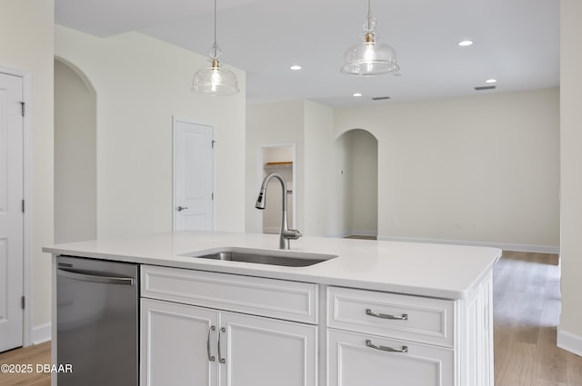 kitchen featuring white cabinetry, an island with sink, sink, stainless steel dishwasher, and light hardwood / wood-style flooring