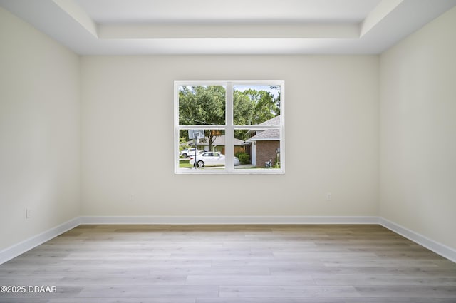 spare room featuring light hardwood / wood-style flooring and a raised ceiling