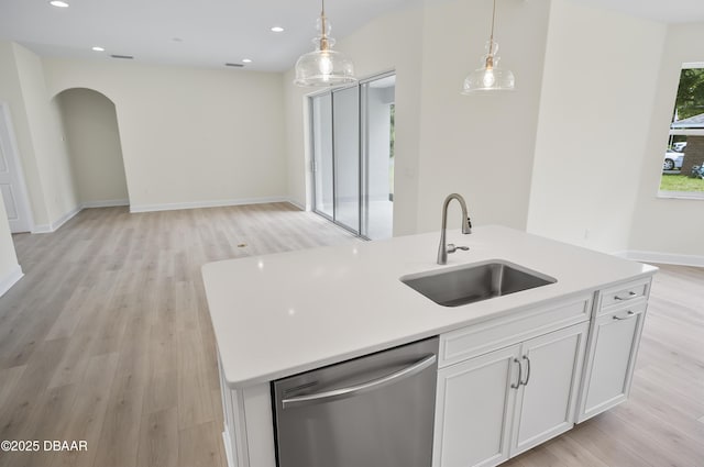 kitchen with stainless steel dishwasher, sink, hanging light fixtures, a kitchen island with sink, and white cabinets