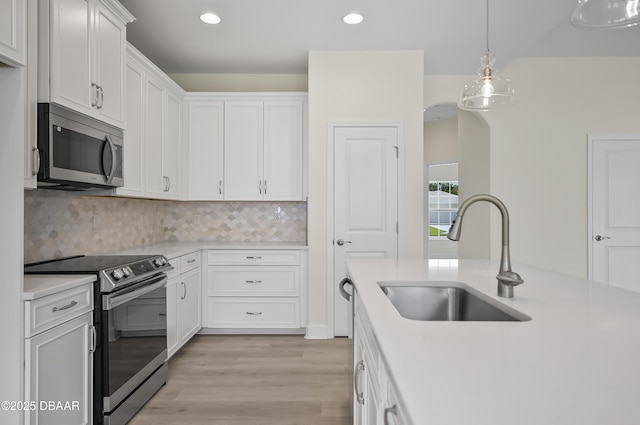 kitchen featuring decorative backsplash, sink, stainless steel appliances, and white cabinetry