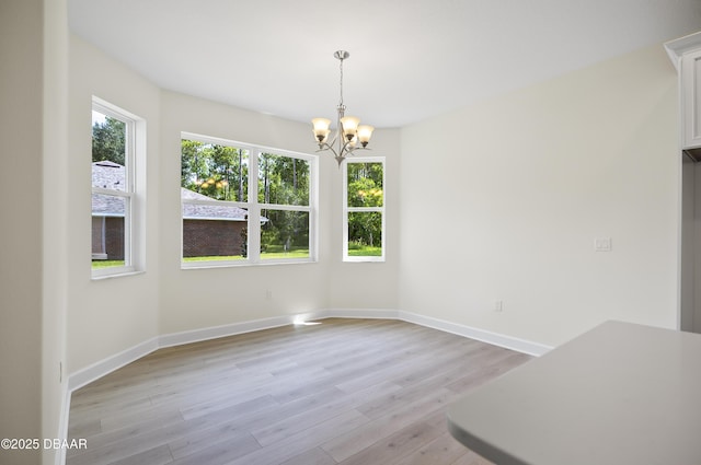 unfurnished dining area featuring a chandelier and light wood-type flooring