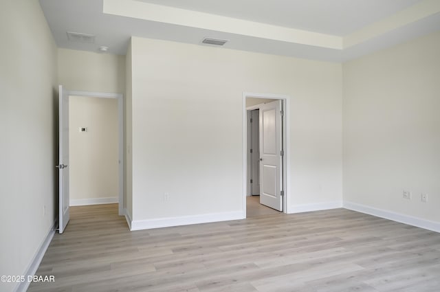 spare room with light hardwood / wood-style floors and a tray ceiling