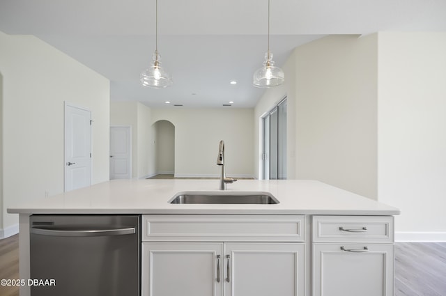 kitchen featuring a kitchen island with sink, hanging light fixtures, stainless steel dishwasher, white cabinets, and sink