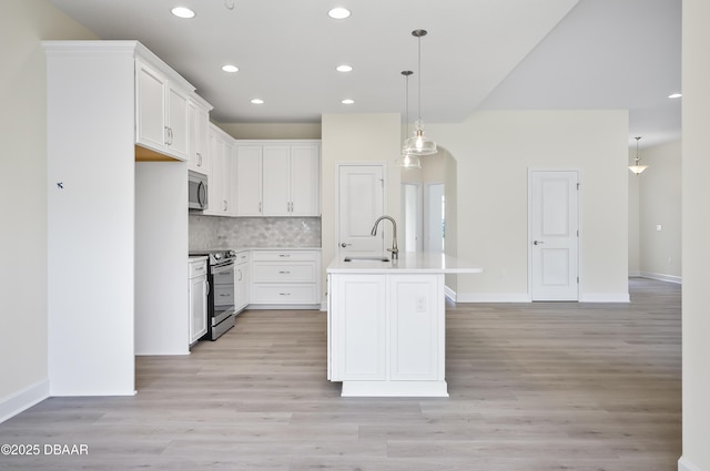 kitchen with white cabinets, backsplash, an island with sink, and stainless steel appliances