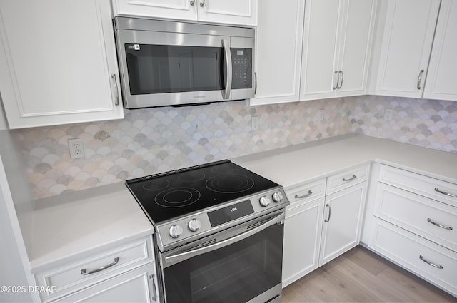 kitchen featuring stainless steel appliances, decorative backsplash, light hardwood / wood-style flooring, and white cabinets