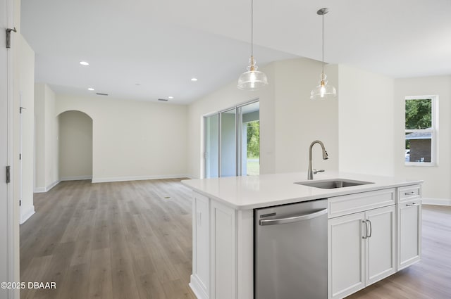 kitchen with white cabinets, stainless steel dishwasher, a center island with sink, and sink