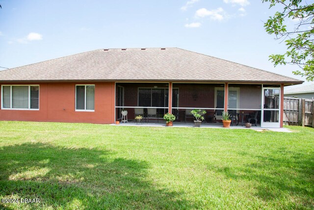 rear view of property featuring a lawn and a sunroom