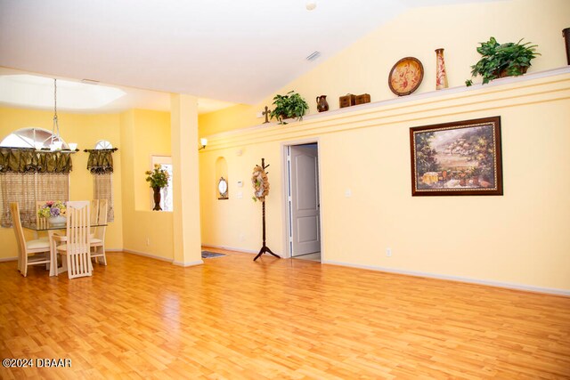 empty room with hardwood / wood-style flooring, a healthy amount of sunlight, high vaulted ceiling, and a notable chandelier