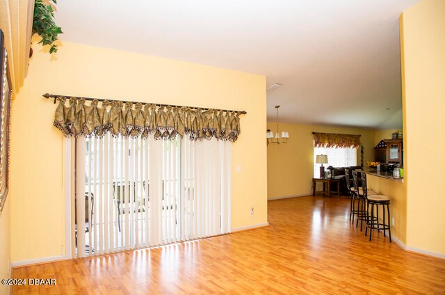 unfurnished room with wood-type flooring, an inviting chandelier, and lofted ceiling