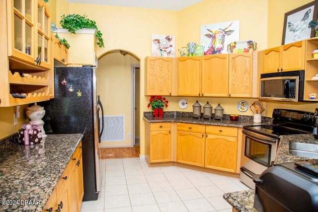 kitchen with dark stone counters, light tile patterned floors, and appliances with stainless steel finishes