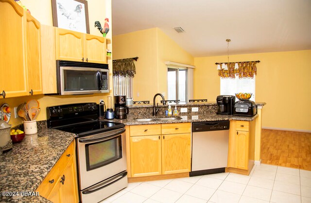 kitchen with dark stone counters, appliances with stainless steel finishes, sink, and light hardwood / wood-style floors