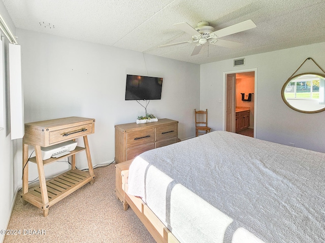 carpeted bedroom featuring ceiling fan, ensuite bathroom, and a textured ceiling