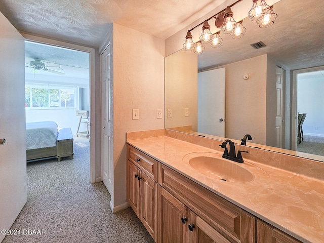 bathroom featuring vanity, ceiling fan, and a textured ceiling