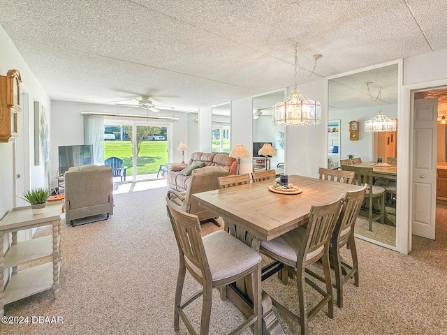 carpeted dining room with ceiling fan with notable chandelier and a textured ceiling