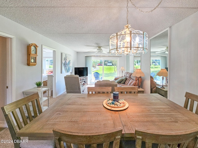 dining area featuring a textured ceiling, a healthy amount of sunlight, and ceiling fan with notable chandelier