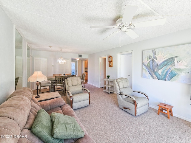 living room featuring carpet, a textured ceiling, and ceiling fan with notable chandelier