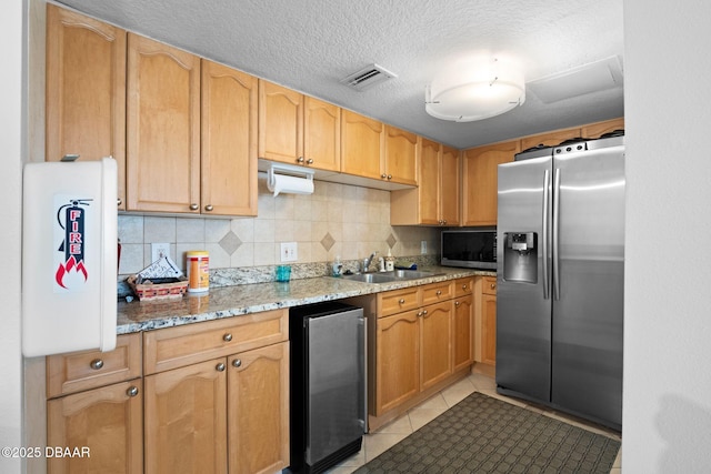 kitchen featuring light stone countertops, sink, light tile patterned floors, and stainless steel fridge with ice dispenser