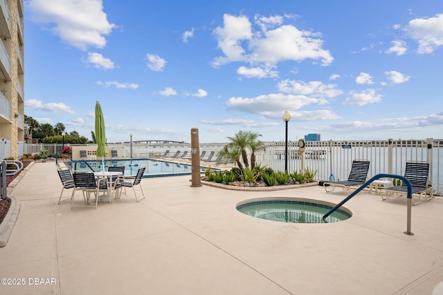 view of pool featuring a water view, a hot tub, and a patio area