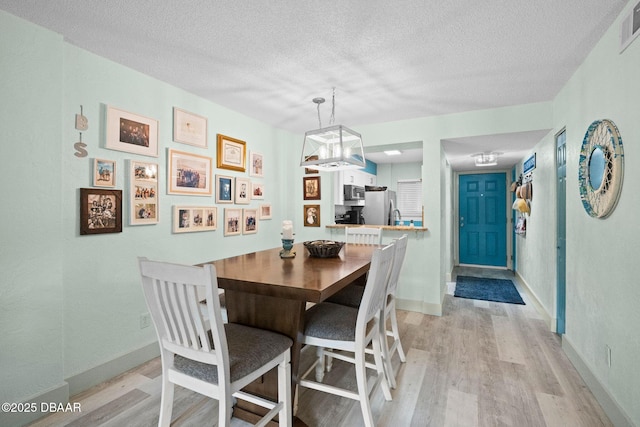 dining room featuring a textured ceiling and light hardwood / wood-style flooring