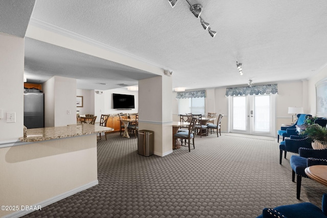 living room with french doors, track lighting, a textured ceiling, and dark colored carpet